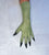 A single long green glove or sleeve worn on a hand, shown against a light textured background. The glove is olive green. Fingers spread.  Palm down