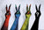 Four human arms raised in peace signs, each printed with a different colorful reptile or dragon skin patterned costume gloves in red, blue, green, and customizable options, against a light gray textured background.