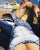 A close-up lifestyle shot of a person wearing a blue, white and black ShapeShifterZ leopard-print swimsuit or unitard on a sunny boat deck, with another shirtless man reclining in the background.
